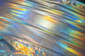 Sparkling colored fabric holographic background. Holographic iridescent surface wrinkled foil pastel