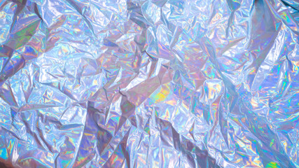 Sparkling colored fabric holographic background. Holographic iridescent surface wrinkled foil pastel