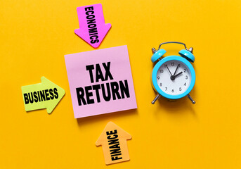 On a yellow background, a blue alarm clock, multi-colored paper arrows with inscriptions and paper...