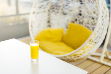 Hanging wicker chair with yellow cushions in minimalistic style outdoor interior. Demonstrating trendy Color of the Year 2021. Illuminating Yellow and Ultimate Gray. Duotone. Depression treatment