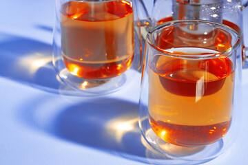 Glass teapot and glass cups of fruit tea on blue background