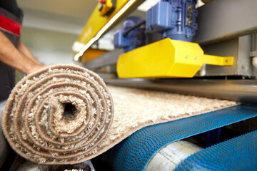 Male worker cleaning carpet on automatic washing machine equipment and dryer in the Laundry room....