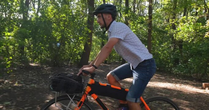 Young male commuter ride on bicycle with halmet in the summer park