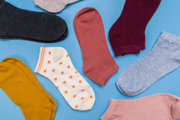 Many multicolored new socks stacked against a blue background. top view.