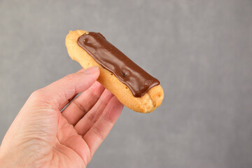 The woman in her left hand holds out an eclair in chocolate glaze