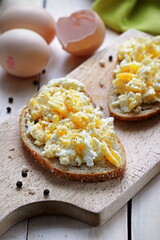 Close up of breakfast sandwiches made of scrambled eggs and fresh bread served on wooden table