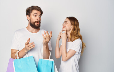 Happy young couple in white T-shirts with packages in hands Shopping is joy