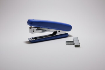A blue stapler and staple isolated on a white background
