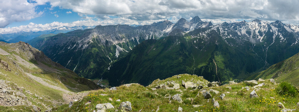 Panoramic view from Pramarnspitze saddle on snow-capped moutain panorama at Stubai hiking trail, Stubai Hohenweg, Alpine landscape of Tyrol Alps, Austria. Summer blue sky, white clouds
