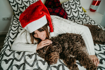 .Beautiful woman playing with her brown spanish water dog in bed on christmas morning. Relaxed, fun and loving. Christmas lifestyle