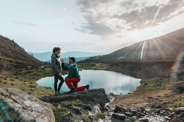 A hiker tourist proposes to marry his girlfriend at dawn in the middle of the mountains....