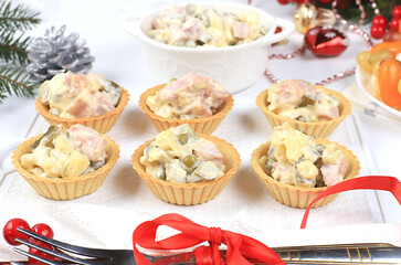 Christmas new year dishes, traditional festive olivier salad with fir branches and cones and decorations on a light table, dish design idea, selective focus, place for text
