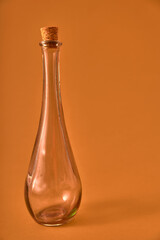 Botella vacía de cristal con pergamino y originales formas sobre fondo solido neutro de color. Iluminación de estudio. Concepto para publicidad con espacio de letrero o edición.