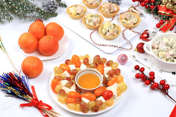 Christmas new year dishes, traditional festive salad olivier and cheese with tomatoes, grapes and honey with fir branches and cones and decorations, dish design idea, selective focus,