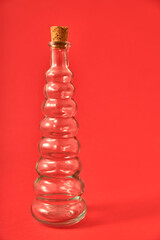 Botella vacía de cristal con pergamino y originales formas sobre fondo solido neutro de color....