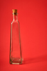 Botella vacía de cristal con pergamino y originales formas sobre fondo solido neutro de color....