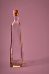 Botella vacía de cristal con pergamino y originales formas sobre fondo solido neutro de color. Iluminación de estudio. Concepto para publicidad con espacio de letrero o edición.