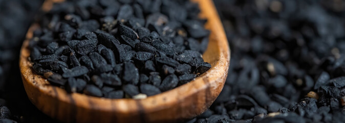 Nigella sativa seeds, close up photography, with a wooden spoon, selective focus.
