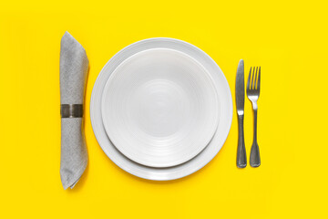 Demonstrating trendy colors 2021 - Gray and Yellow. Food concept. table setting Grey plates, napkin and Cutlery on a yellow background. concept of takeaway food delivery menu