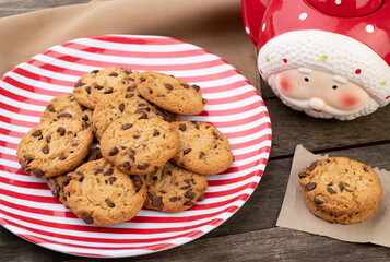 Chocolate chip cookies on a red and white plate with santa claus tea pot