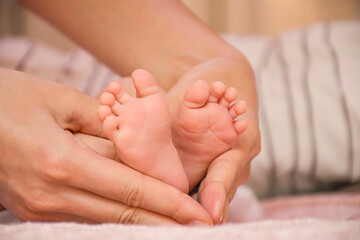 Close-up baby feet in mother hands. Tiny legs of newborn child. First days of life. Mom and her baby. Image of maternity and family.