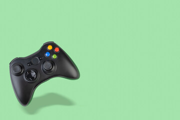 Floating videogame controller over green background with copy space © Odu Mazza
