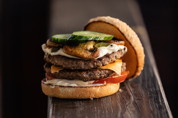 Tasty humburger with tomatoes and red onion. Brown wooden background.