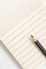 Note pad with lines and black pencil with a white background