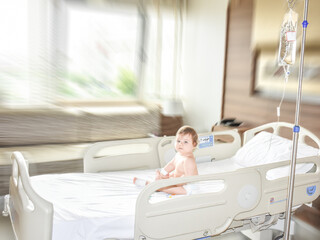 Little sick baby on a drip receiving a saline solution intravenously in the hospital or clinic....