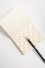 Note pad with lines and black pencil with a white background