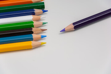 Pack of colorful pencils arranged to depict odd man out with a white background