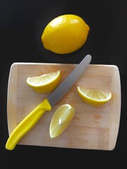 yellow knife and lemon slices on wooden board