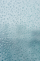 Melting snow on the glass, drops of water condensation on the window, and transparent glass of the window in cold winter, winter landscape outside the window, close-up.