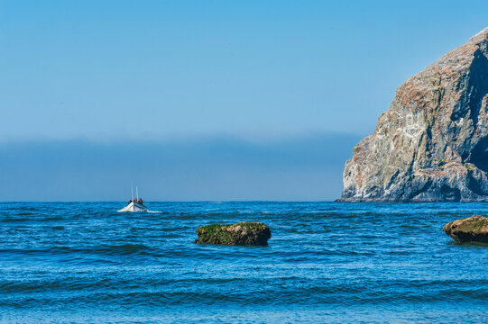 Dory board passes by Haystack rock