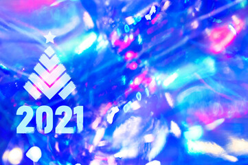 Christmas background-garlands with colorful lights on a decorated Christmas tree, bokeh, Happy New Year 2021 colored symbol and text for seasonal holidays flyers, greetings and invitations cards