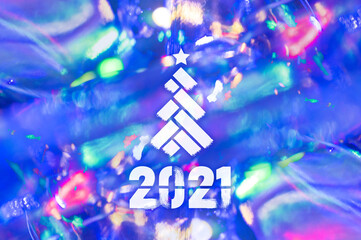 Christmas background-garlands with colorful lights on a decorated Christmas tree, bokeh, Happy New Year 2021 colored symbol and text for seasonal holidays flyers, greetings and invitations cards