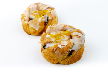 Two twisted lemon and sultana Danish pastries covered with flavoured icing and lemon shred.