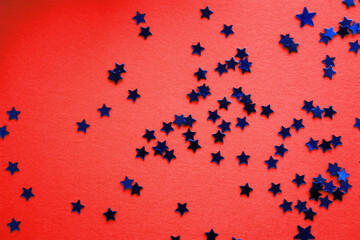 Blue stars glitter shiny confetti on a red background. Christmas concept. Flat lay. Top view....