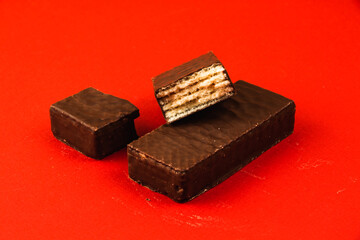 Sweets food concept, composition of chocolate waffle bars on a red background, flat lay, copy space