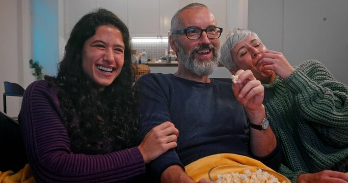 Family watching television and eating popcorn together at home