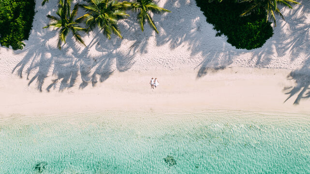 A couple relax on the beach on the white sand near sea. Aerial shoot by drone