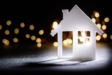 Small cardboard house on a dark winter background.
