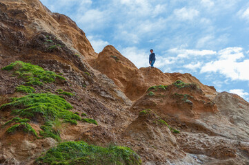 Boy explores the sandstone ledges at the base of the beach at Pacific City Oregon