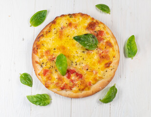 Pizza with cheese and tomatoes on white wooden background