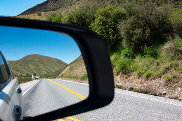 Lindis Pass highway and hills in rear vision mirror