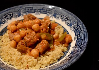 Meet and chickpea served on top of pilaff with black background
