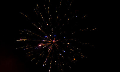 Obraz premium Firework exploding in the dark night sky to celebrate the new year. Colorful fireworks emitting sparks. New Years Eve Celebration. Particle Effect, Glowing, Blazing, Twinkling, Glistening.