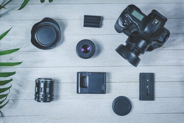 Flat lay with different photoaccessories on the table: camera, lenses, battery, charger, synchronizer, and lens covers