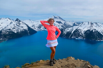 Hiker on the top of mountain above turquoise lake and snowcapped peaks. Garibaldi Lake. Whistler. British Columbia. Canada