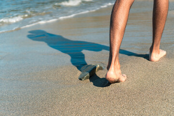 Naked feet of a man walking on a beach in the morning